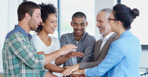 Happy staff putting their hands in the middle of a huddle