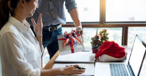 A man giving a Christmas present to one of his work colleagues 