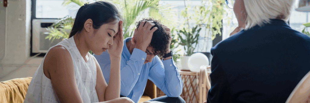 a distressed looking man and women in a work meeting