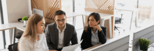 a man sitting between two women smiling whilst looking at a contract